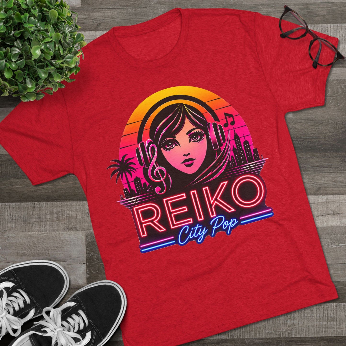 Front view of the Reiko Takahashi City Pop Sunset Logo Tee in Vintage Red, printed on a premium Next Level tri-blend T-shirt and displayed in a styled flat lay with sneakers, eyeglasses, and a green plant. Features retro neon artwork inspired by the song "Sunset Road."